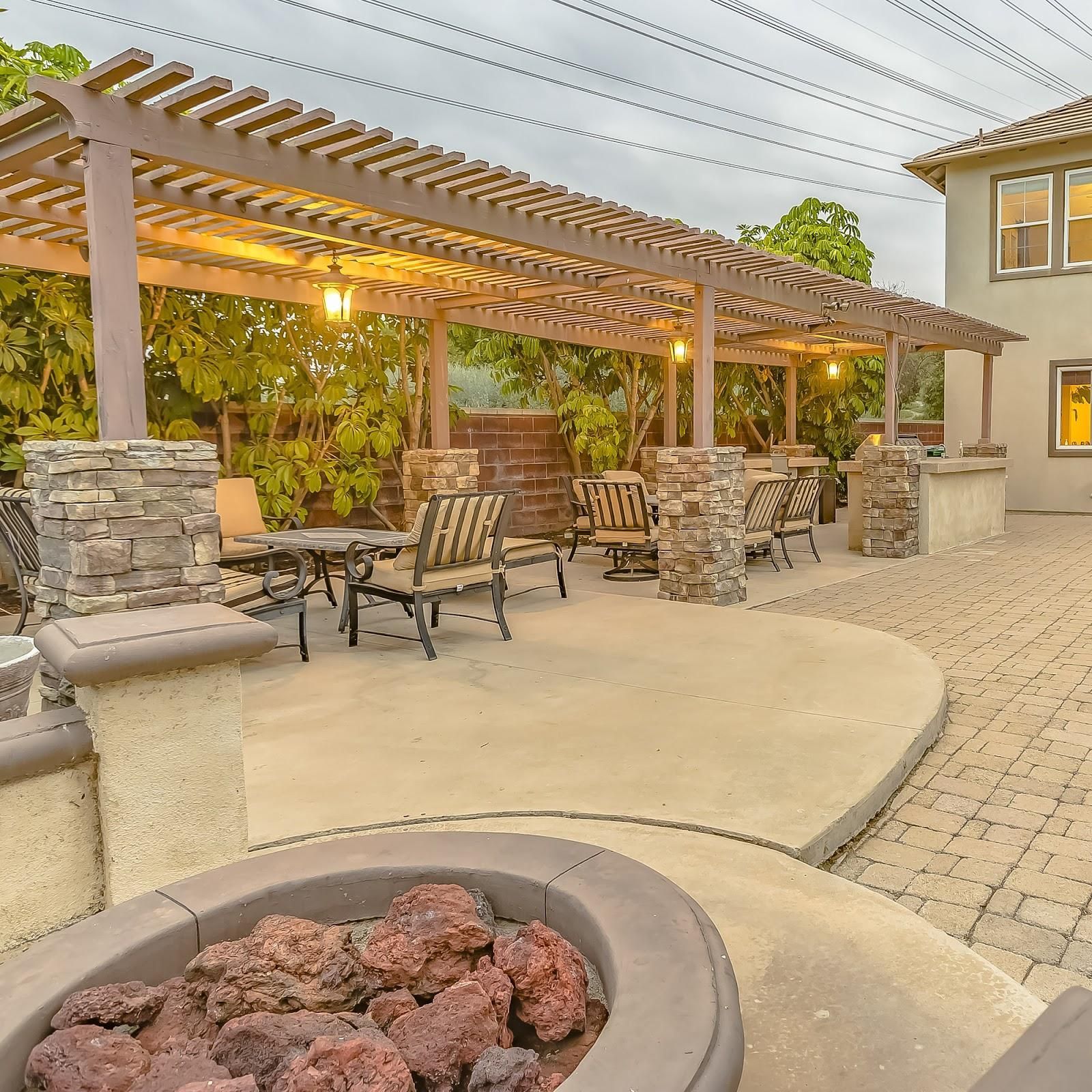 A patio with a fire pit and chairs under a pergola