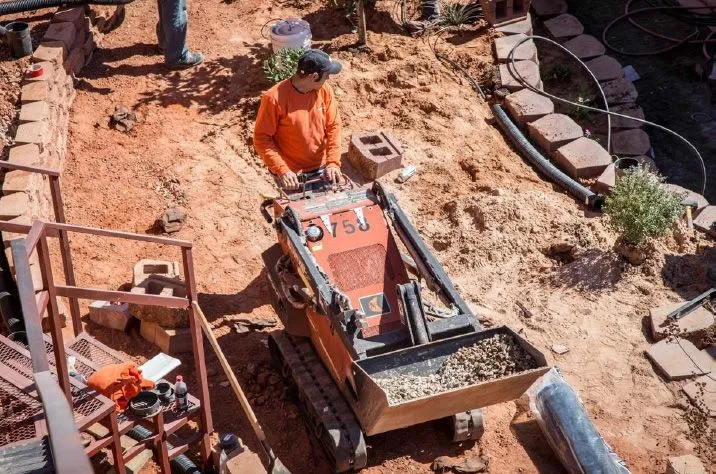 A man is driving a small bulldozer on a dirt road.