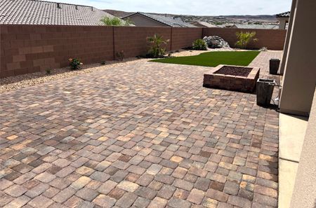 A brick patio with a fire pit in the middle of it.
