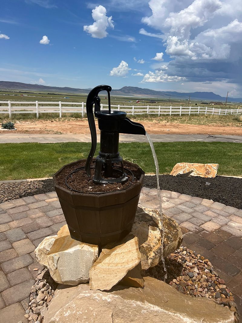 A water pump is sitting on top of a bucket on a patio.