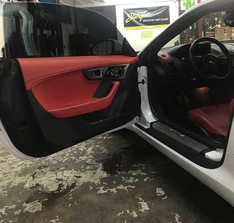 White car interior with red leather door and seats, door open.