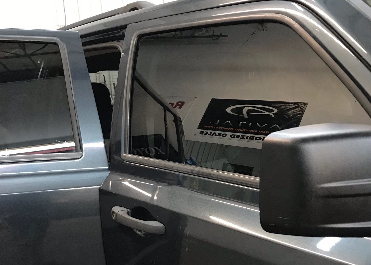 Dark gray SUV with tinted windows, door open. A logo is visible through the window.