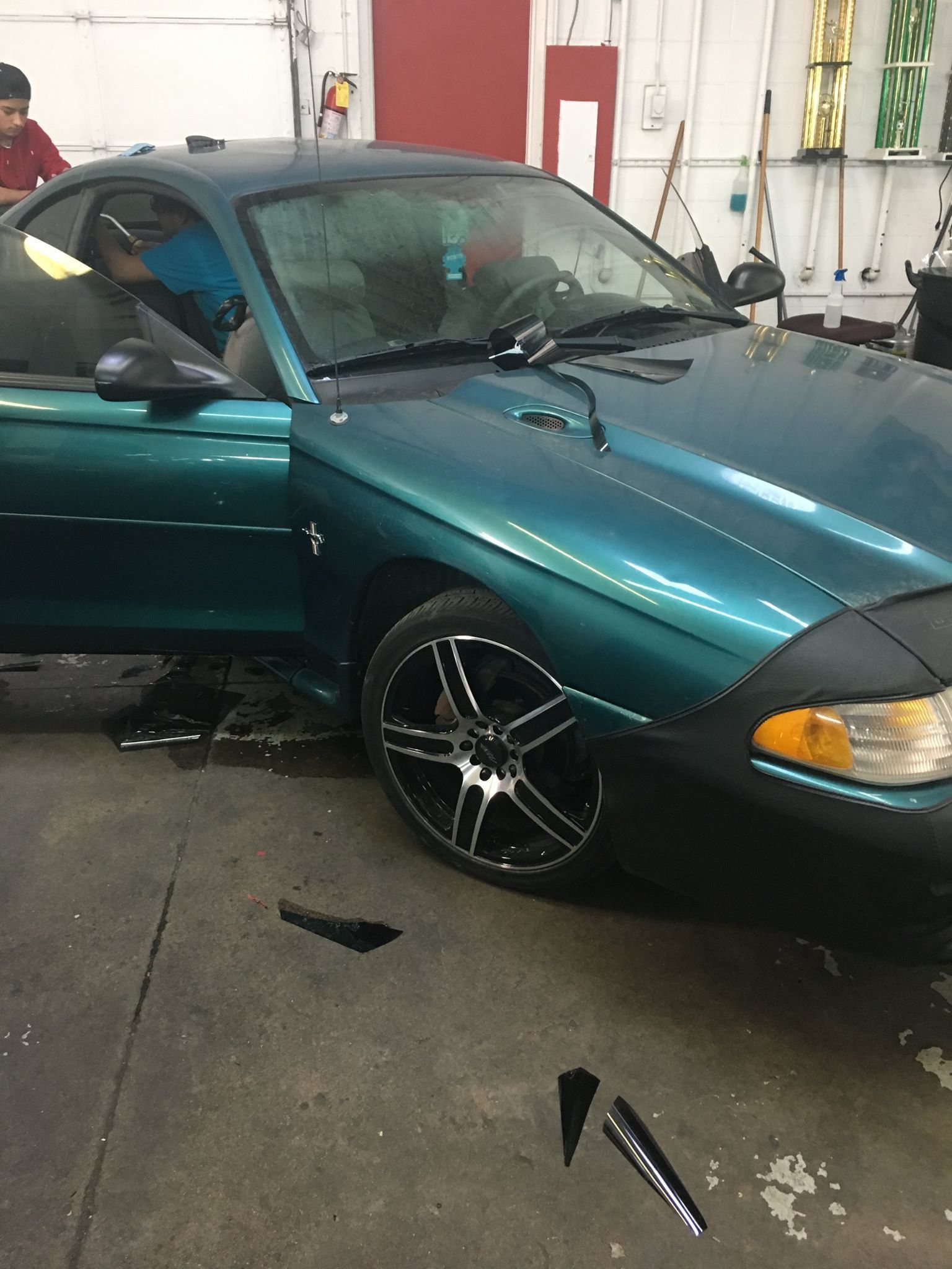 Teal Ford Mustang in a garage with a person inside, window tinting.