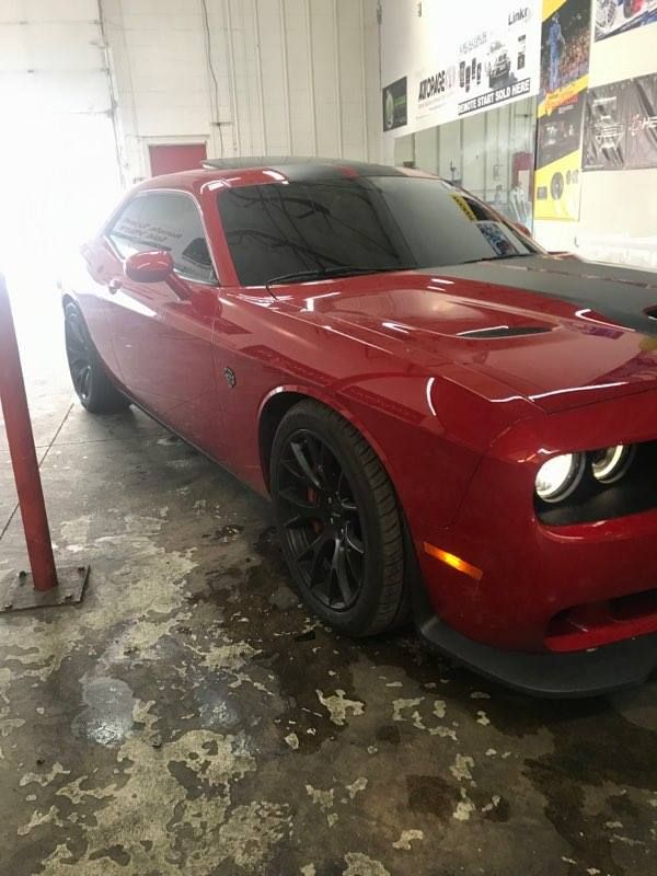 Red Dodge Challenger with black accents parked inside a garage.