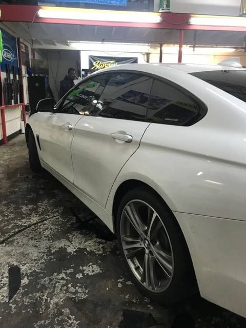 White BMW coupe with tinted windows inside a garage.