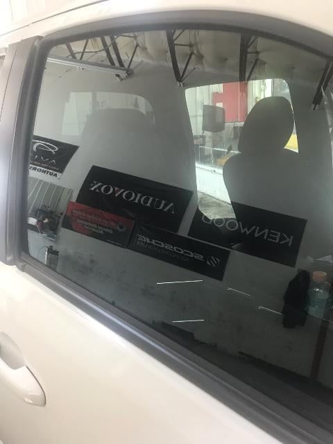 White car window with stickers, reflecting interior and a building.