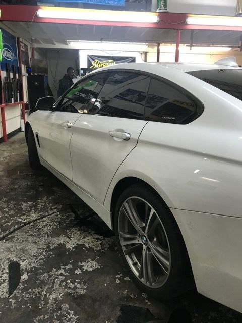 White BMW coupe with tinted windows in a garage.