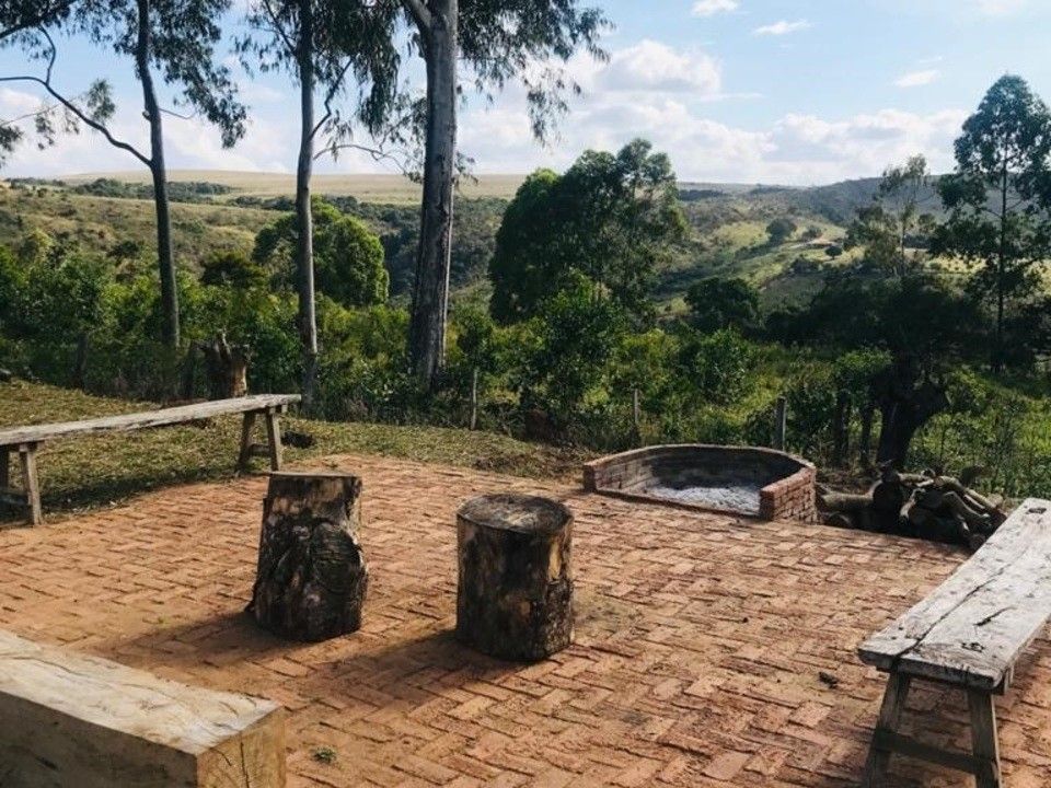 Pátio externo de tijolos com bancos, tocos de árvores, fogueira e vistas panorâmicas do vale.