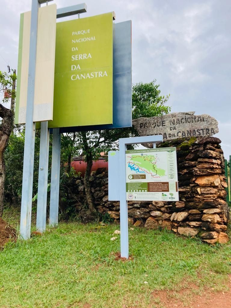 Placa indicativa do Parque Nacional da Serra da Canastra, Brasil. Painéis verdes e bege, mapa em um poste. Fundo de parede de pedra.