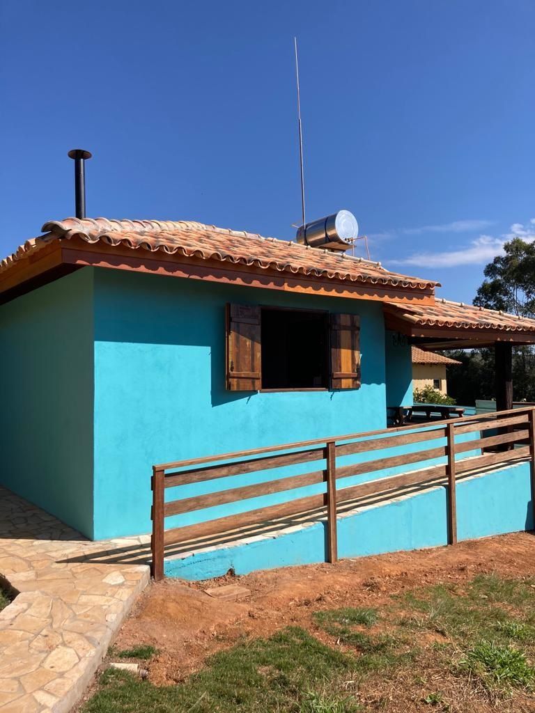 Prédio azul com venezianas de madeira e uma rampa, sob um céu azul.