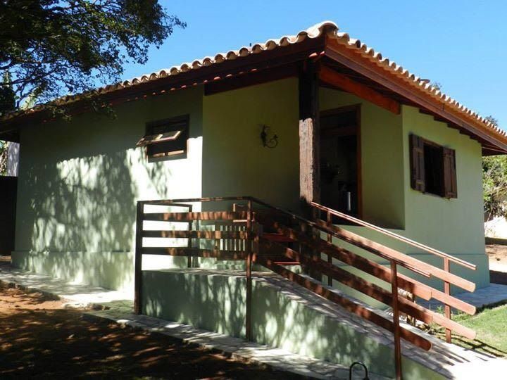 Estufa com grades de madeira e degraus que levam à entrada, telhado marrom.