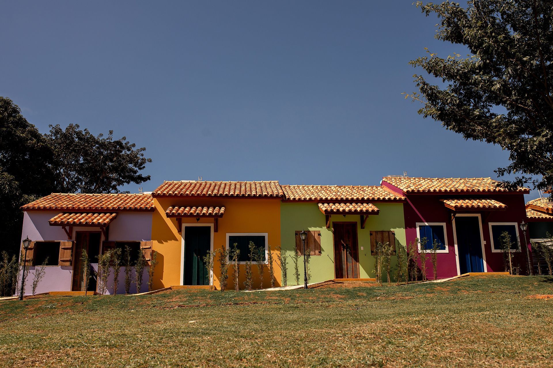 Fileira de casas coloridas com telhados de telha, contra um céu azul.