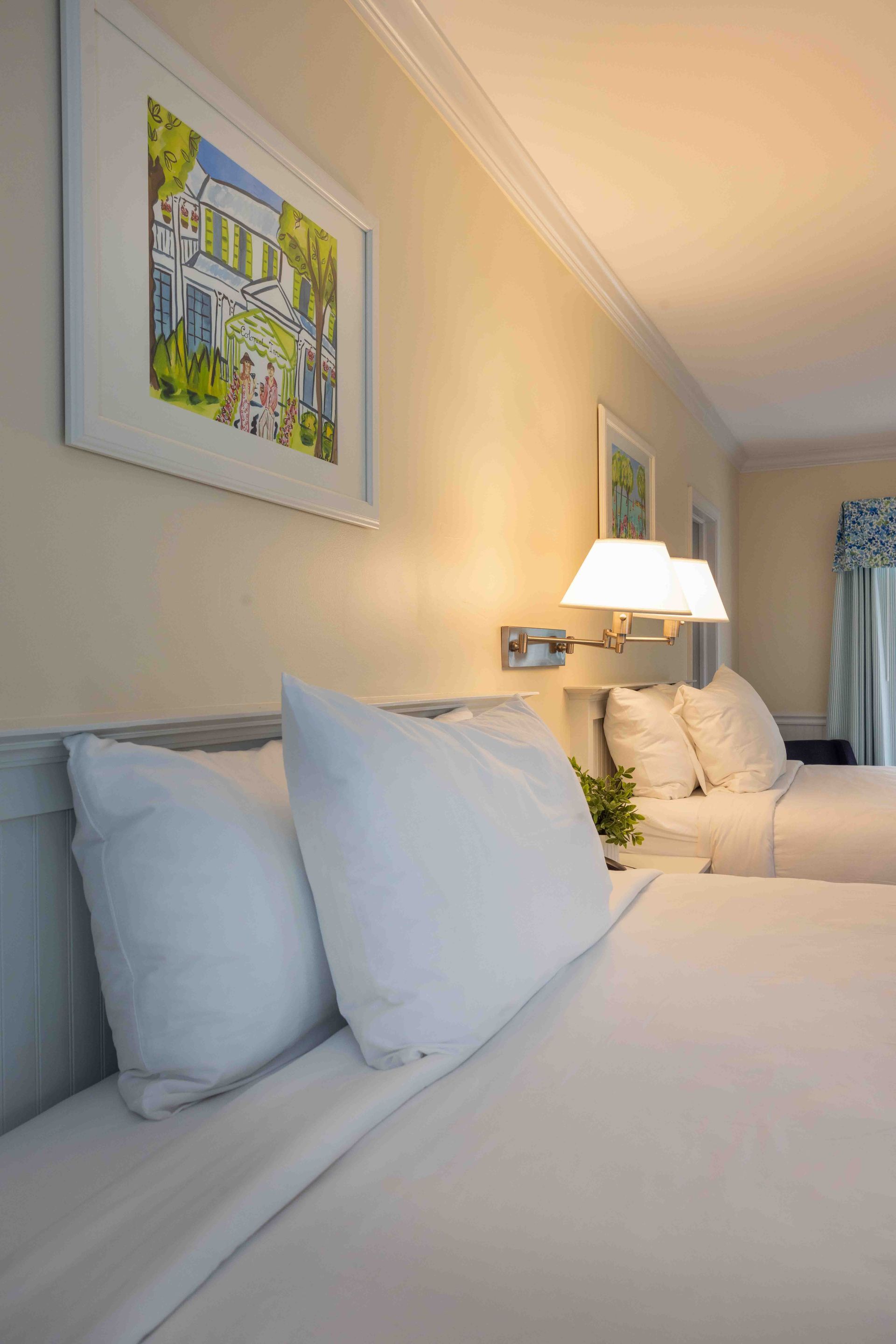 A hotel room with two beds and a painting on the wall.