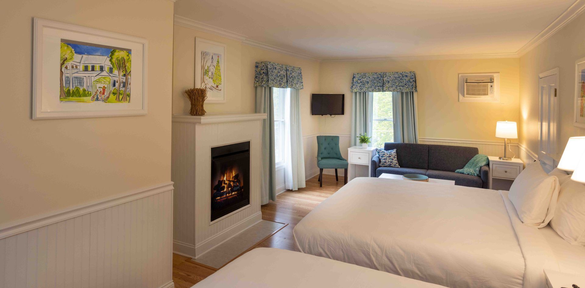 A hotel room with two beds , a couch , and a fireplace.