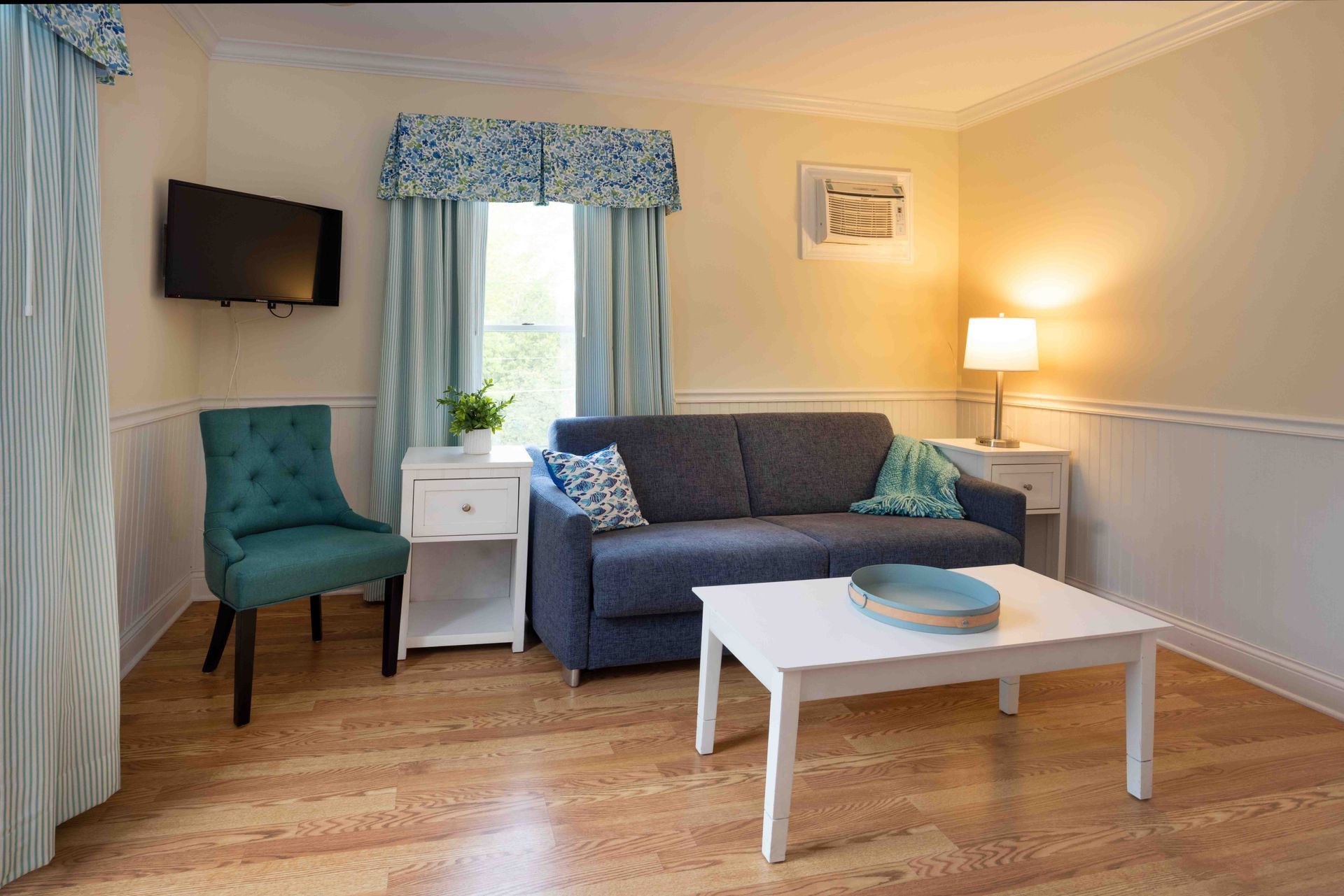 A living room with a couch , chair , coffee table and television.