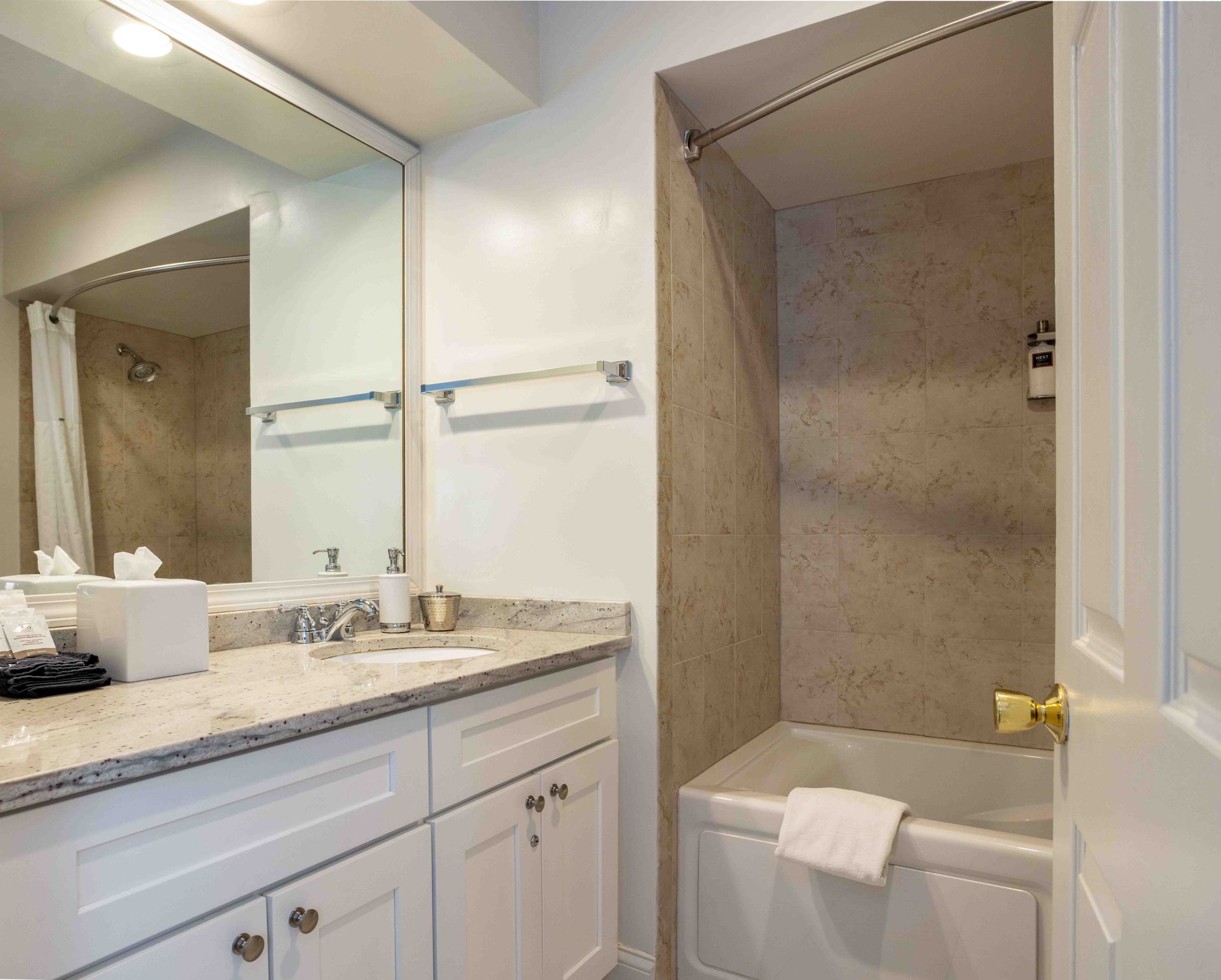 A bathroom with a tub , sink , mirror and shower.