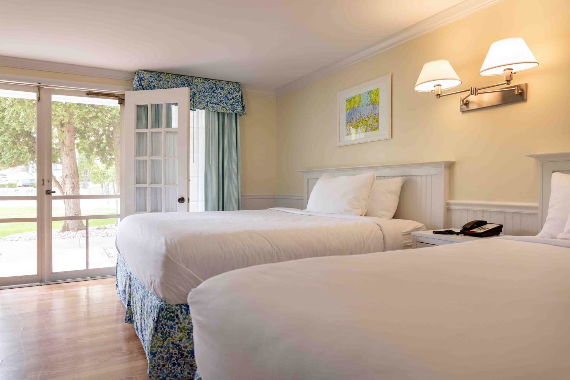 A hotel room with two beds and a sliding glass door.