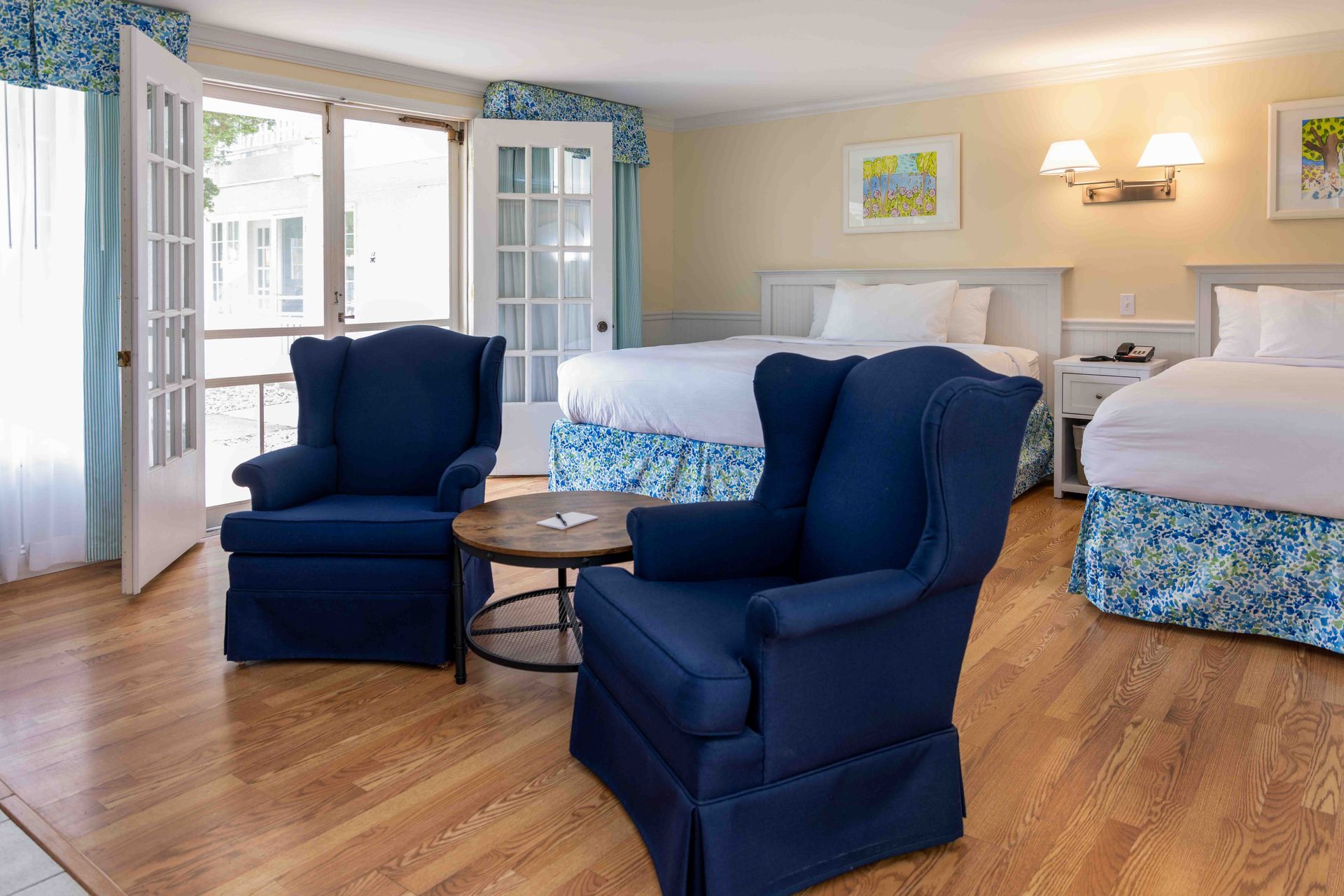 A hotel room with two beds , two chairs and a table.