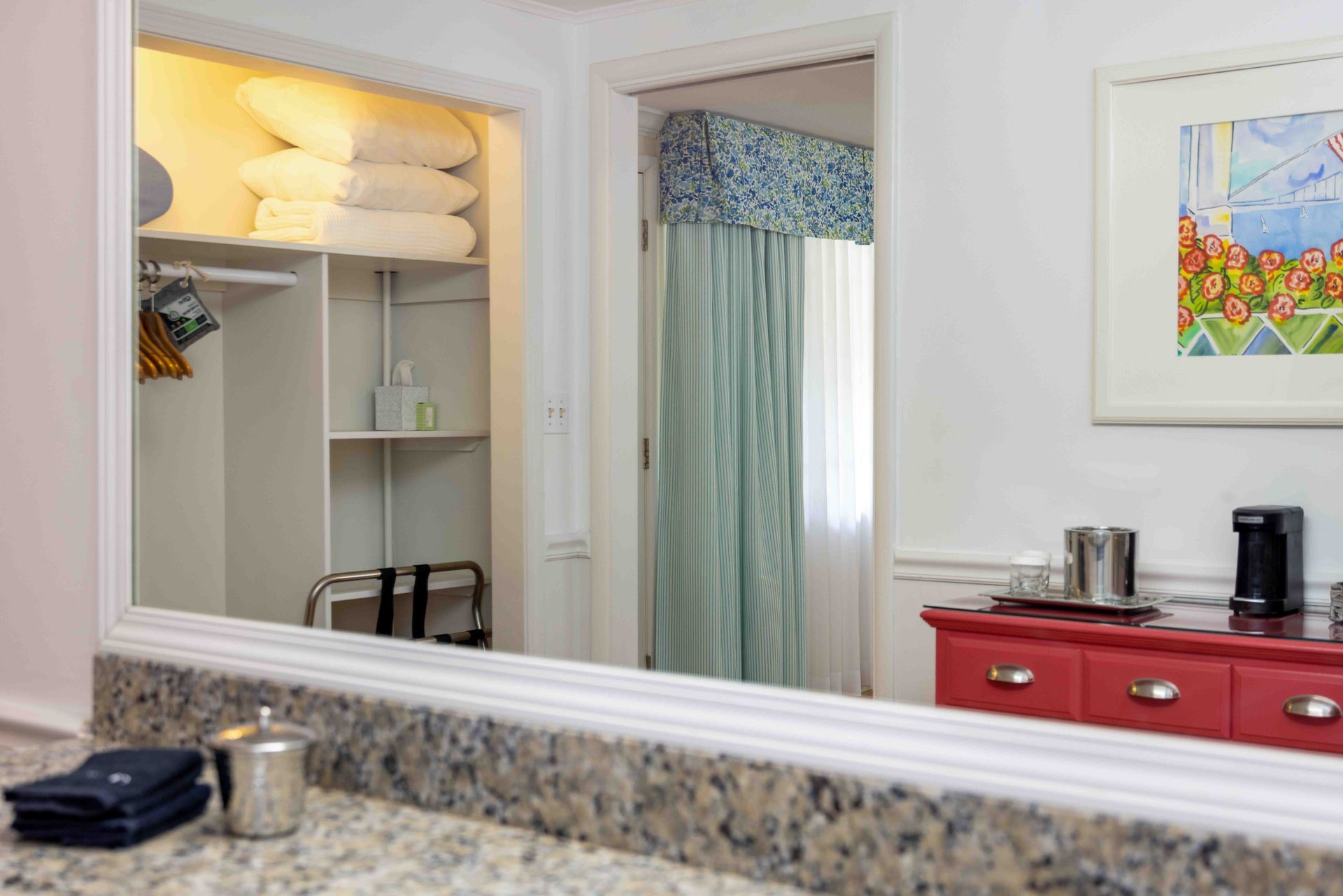 A bathroom with a large mirror and a red dresser.