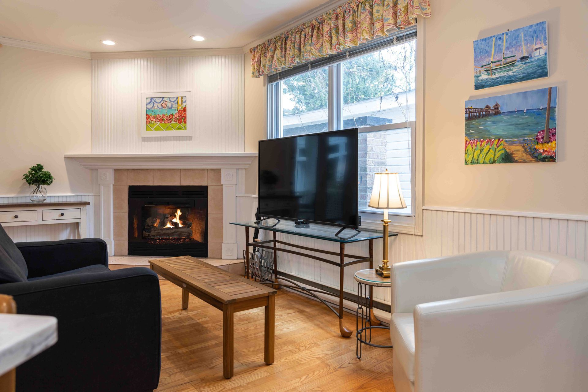 A living room with a fireplace , two chairs , a coffee table and a flat screen tv.