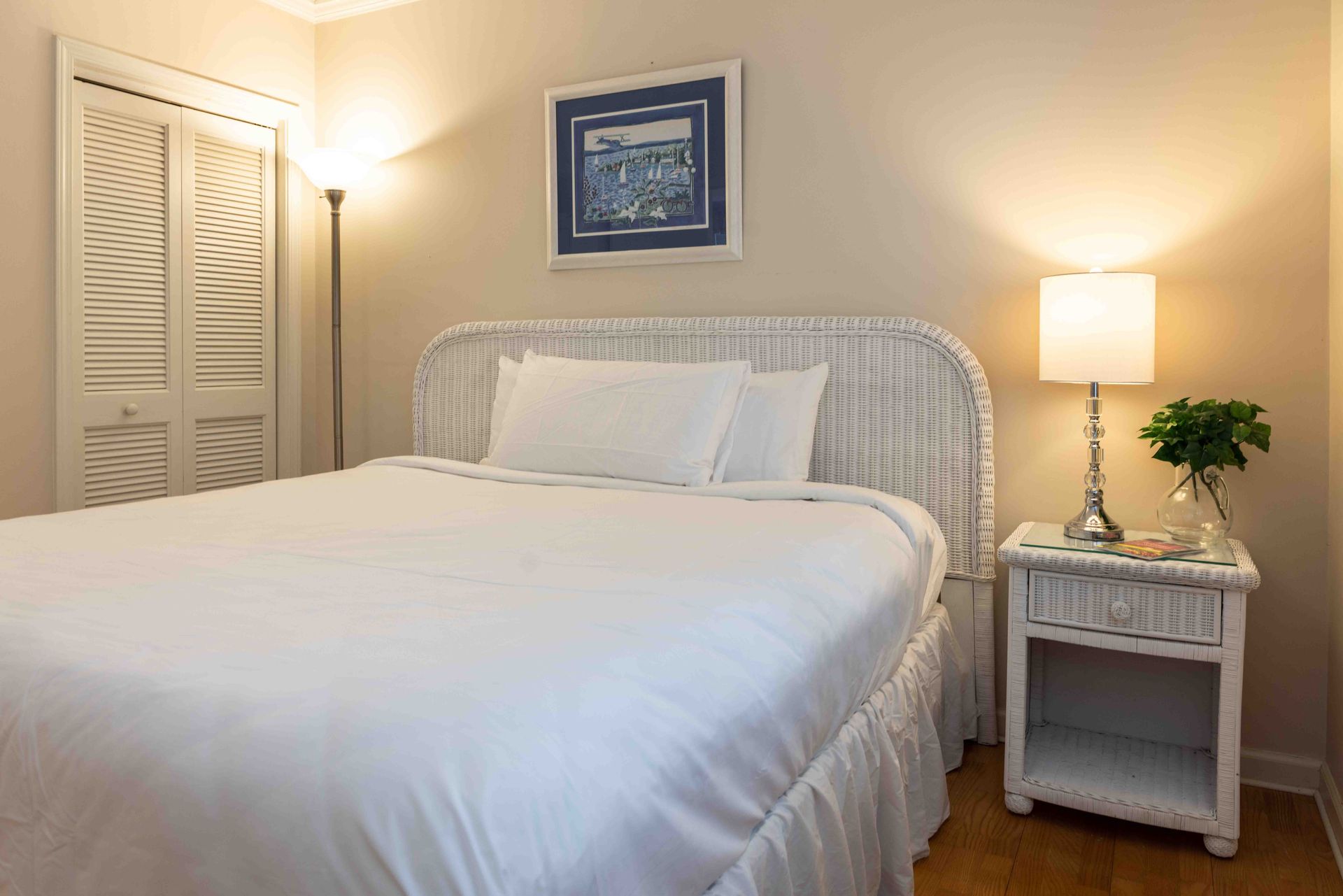 A bedroom with a bed , nightstand , lamp and closet.