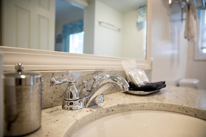 A bathroom sink with a soap dispenser and a mirror.