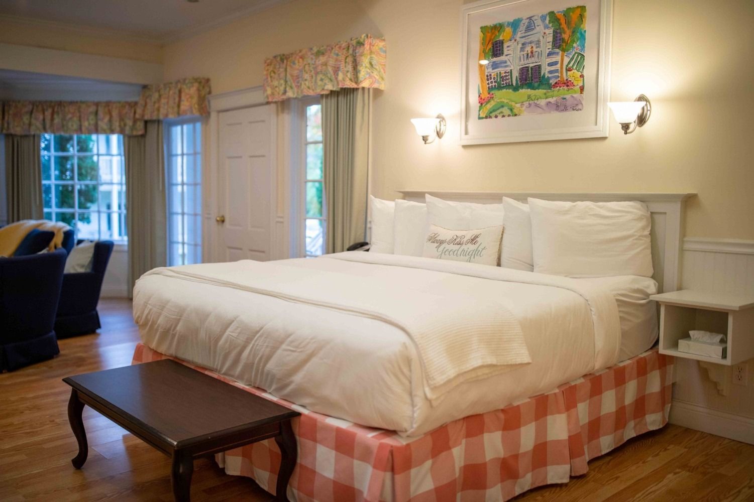 A hotel room with a king size bed and a table.