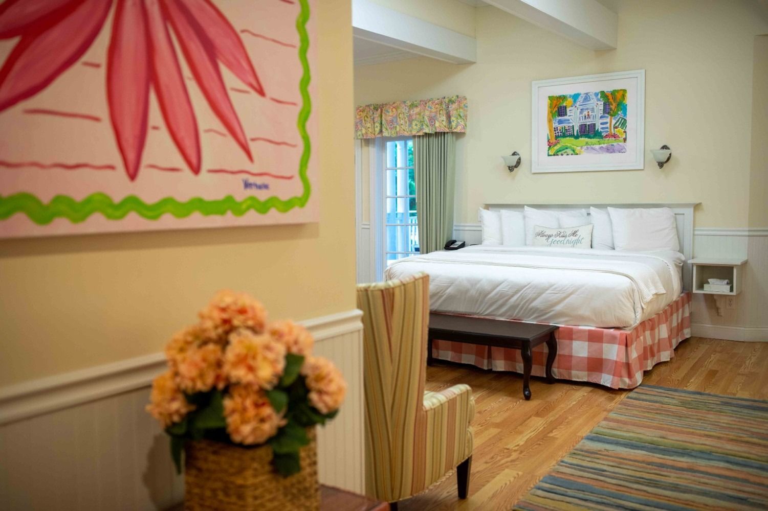 A hotel room with a bed , chair , and painting on the wall.