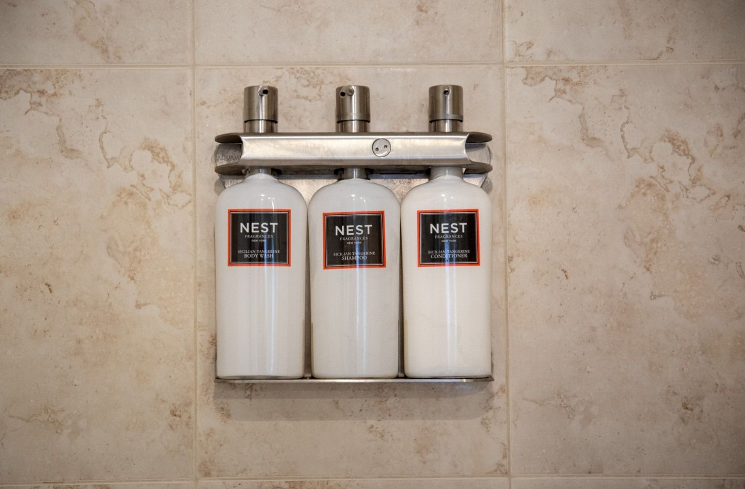 Three bottles of nest lotion are hanging on a wall.