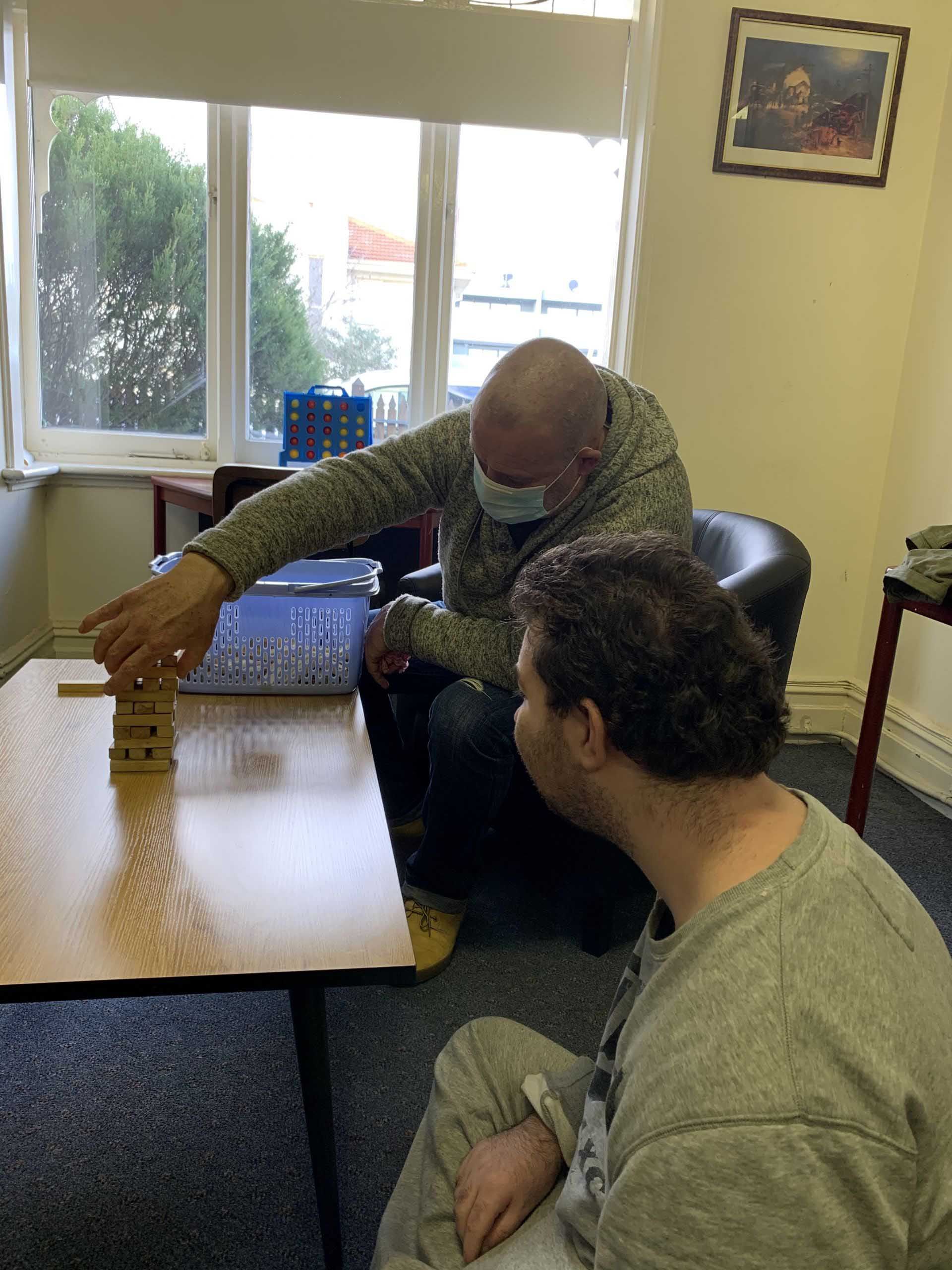 Two Men Are Sitting at a Table Playing a Game — Keilor East, VIC — North West Melbourne Family Respite