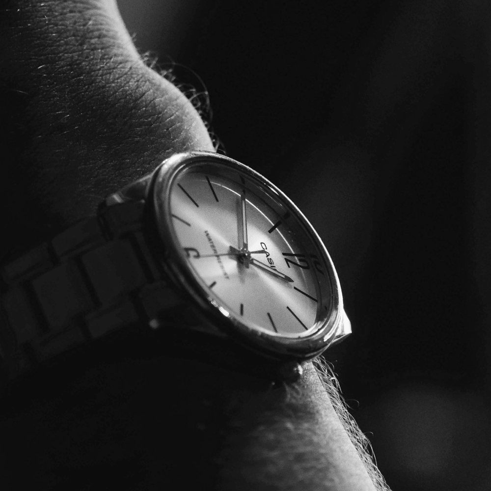 Black and silver chronograph watch with a black leather strap against a white background.