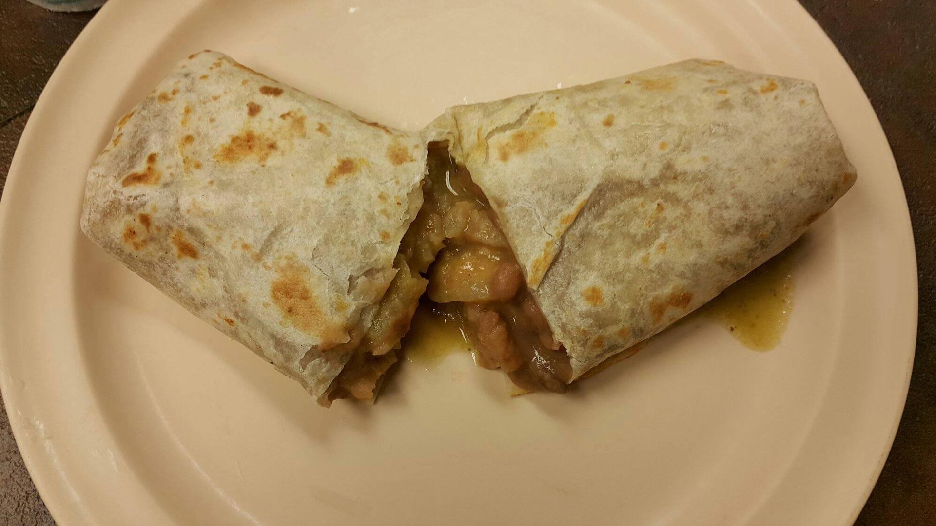 A burrito is cut in half on a white plate.