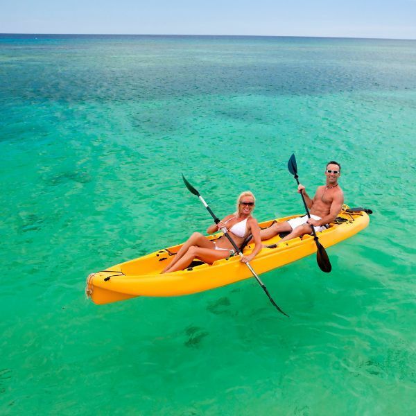 A man and a woman are in a yellow kayak in the ocean