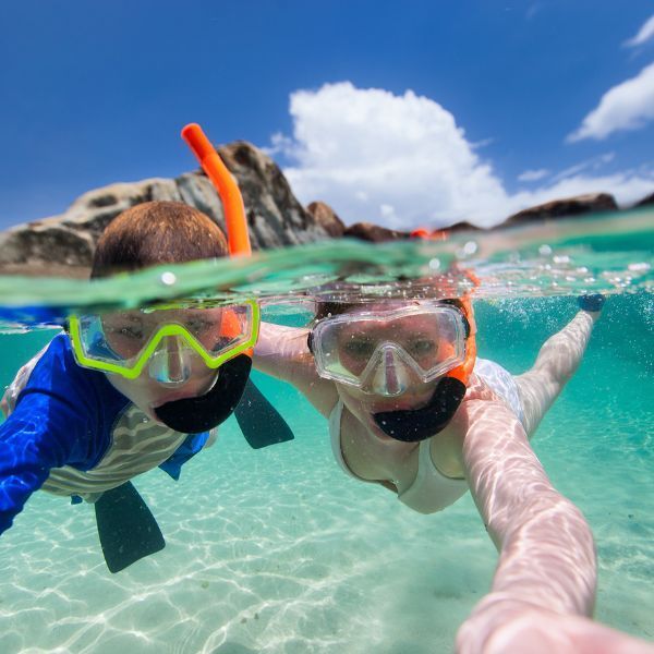 A boy and a girl are snorkeling in the ocean