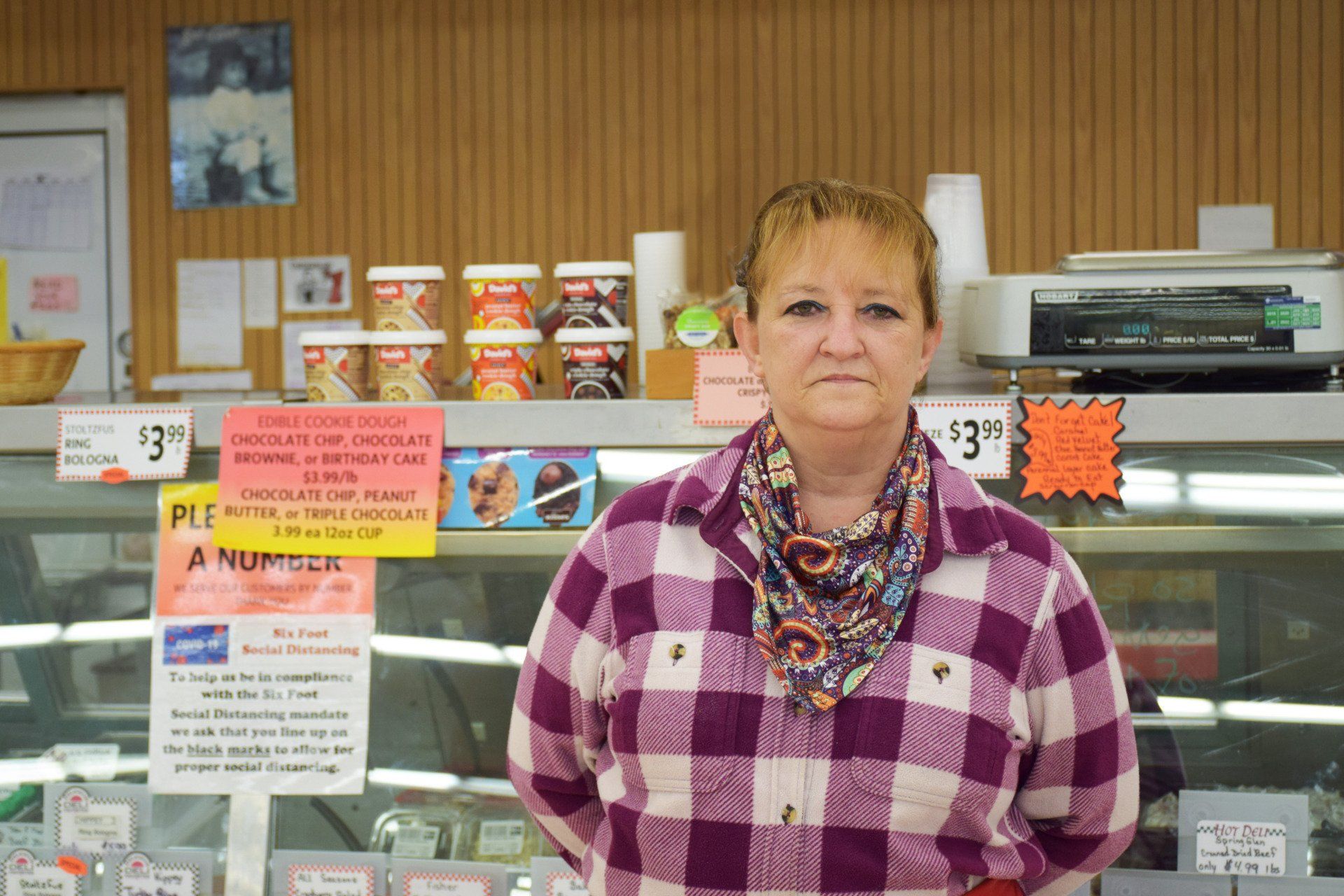 A woman in a plaid shirt is standing in front of a display case in a store.
