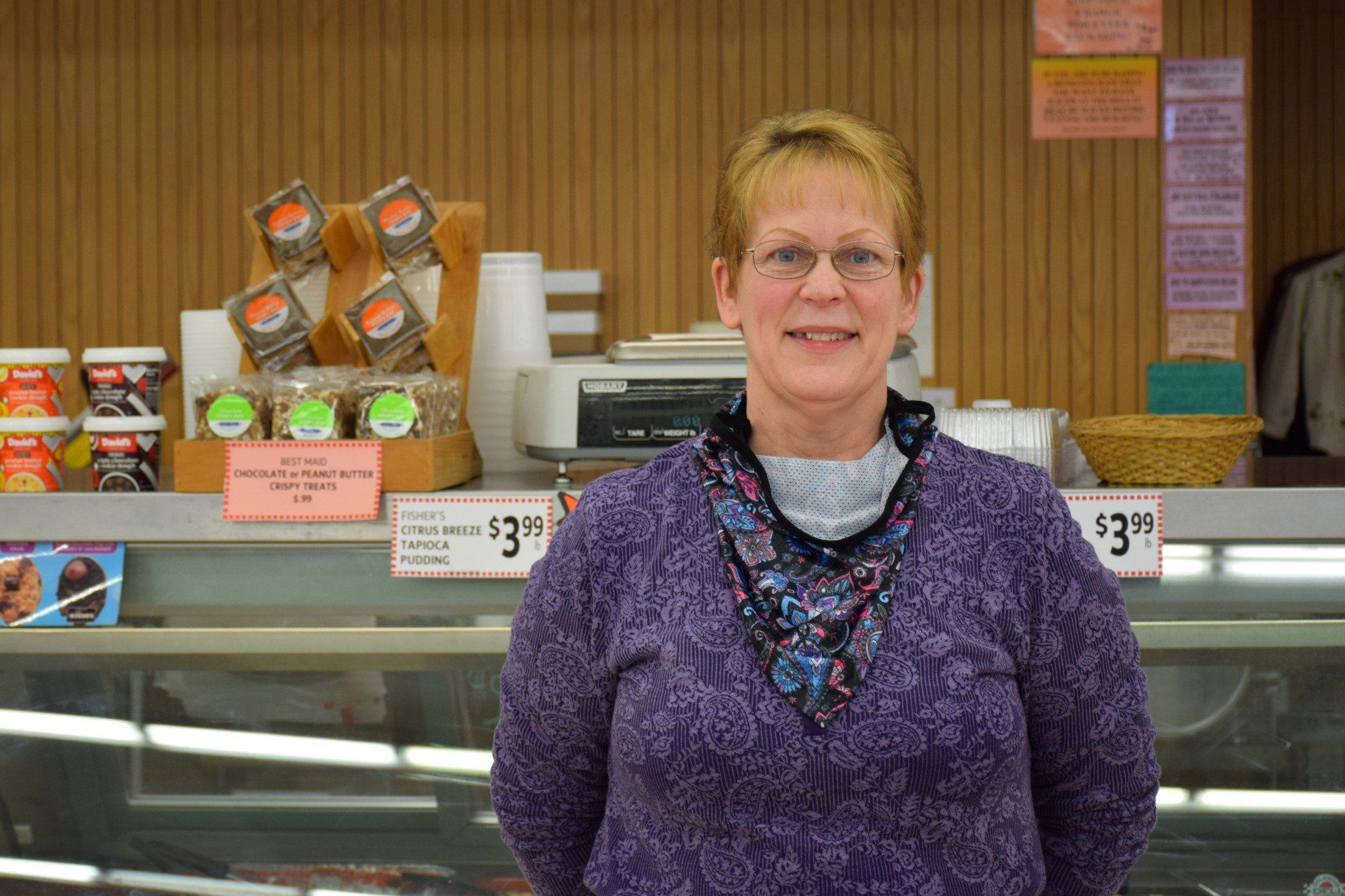 A woman in a purple sweater is standing in front of a display case in a store.