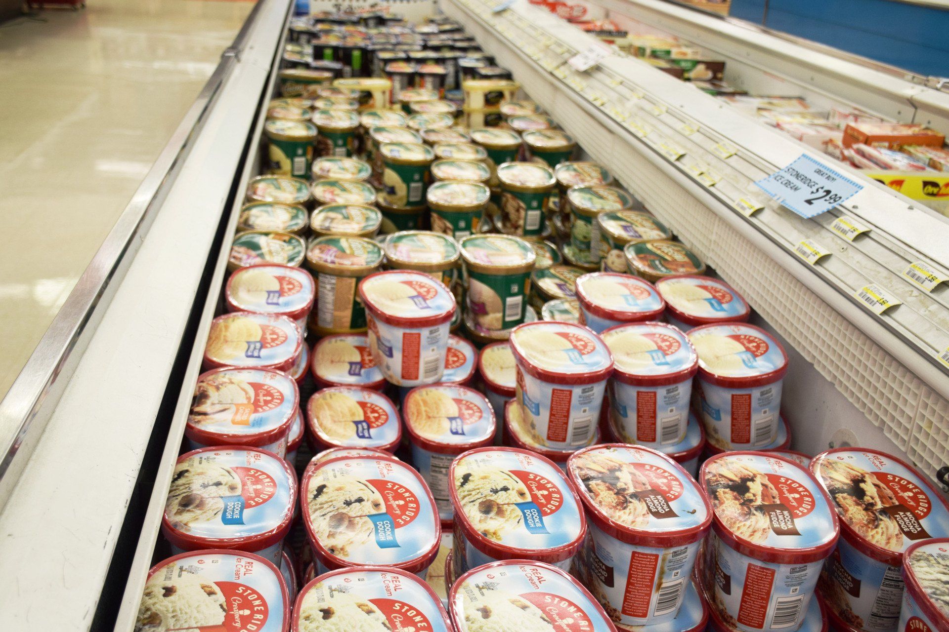 A refrigerator filled with lots of ice cream cups in a grocery store.