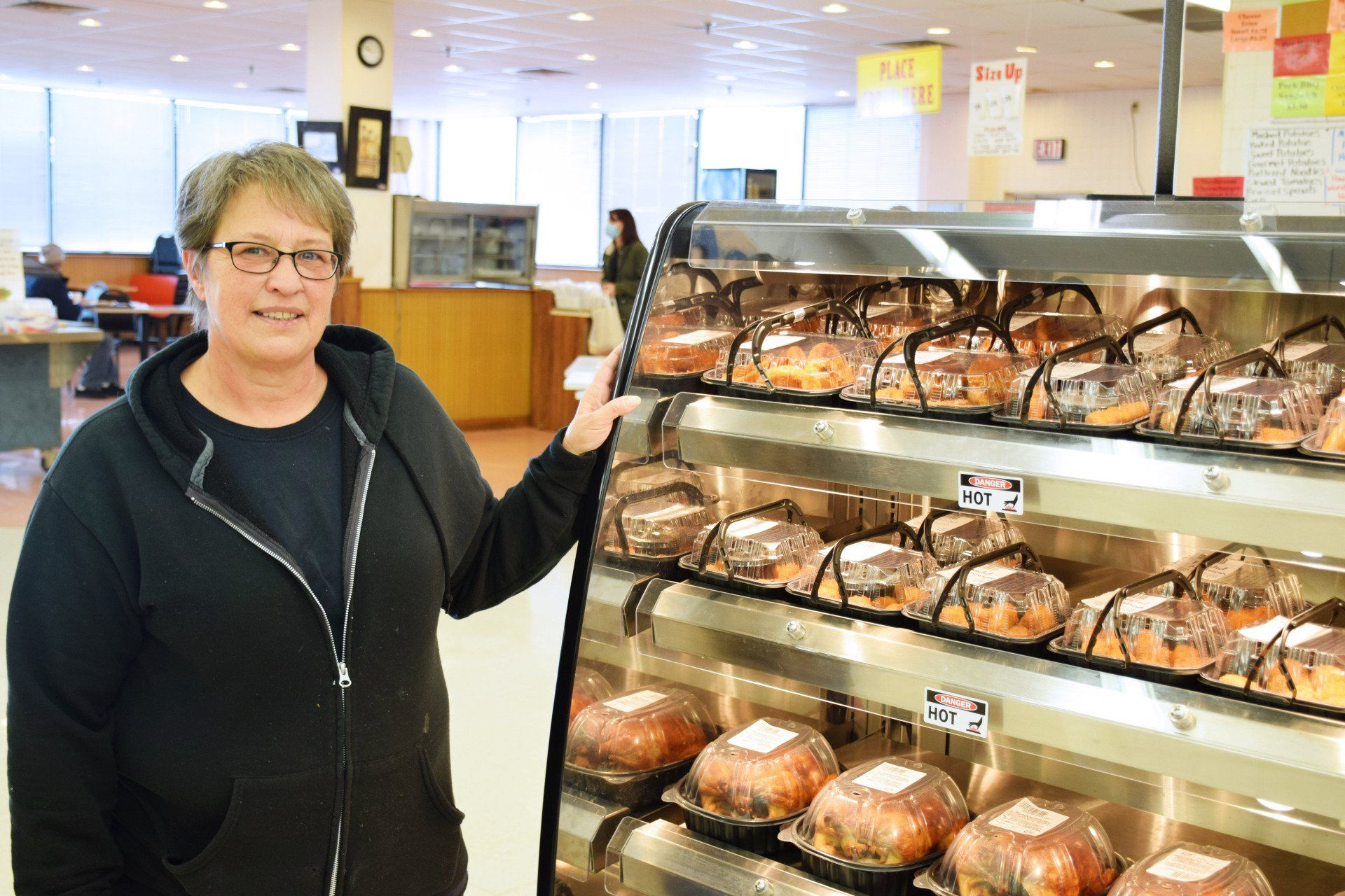 A woman is standing in front of a display of bread in a bakery.