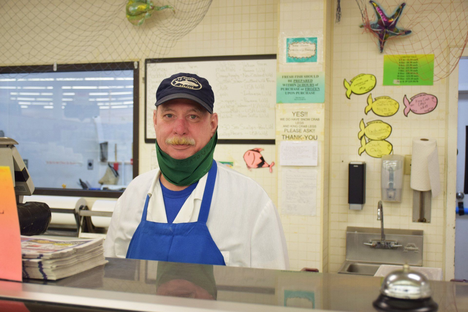 A man wearing a hat and apron is standing behind a counter.