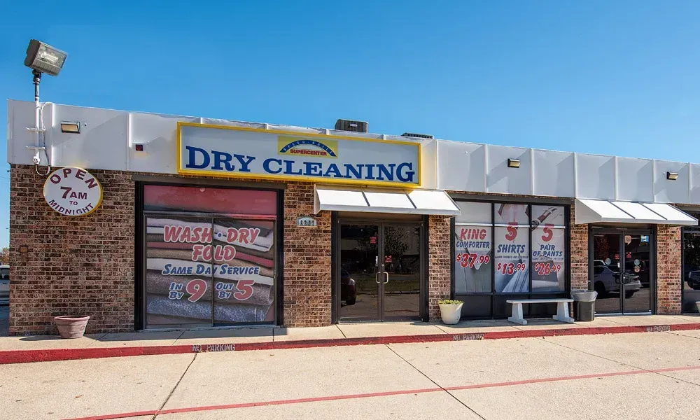 Dry cleaning business exterior with signage, brick facade, and clear blue sky.