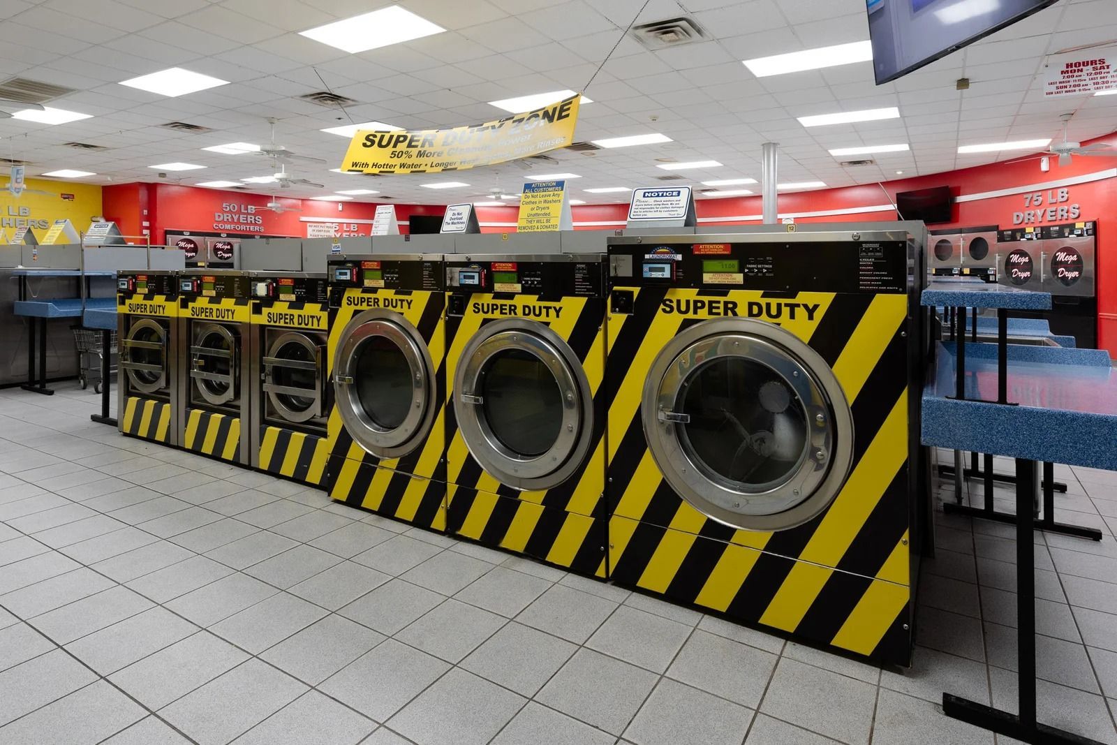 Row of yellow and black striped washing machines in a brightly lit laundromat.