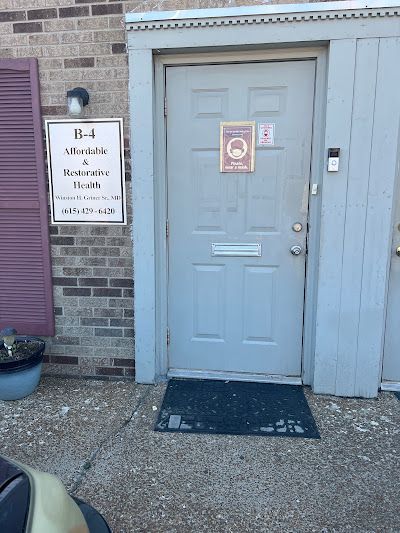 A Gray Door With a Sign on It and a Black Mat in Front of It