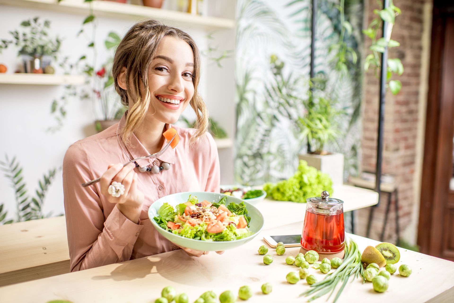 A Woman is Sitting at a Table Eating a Salad