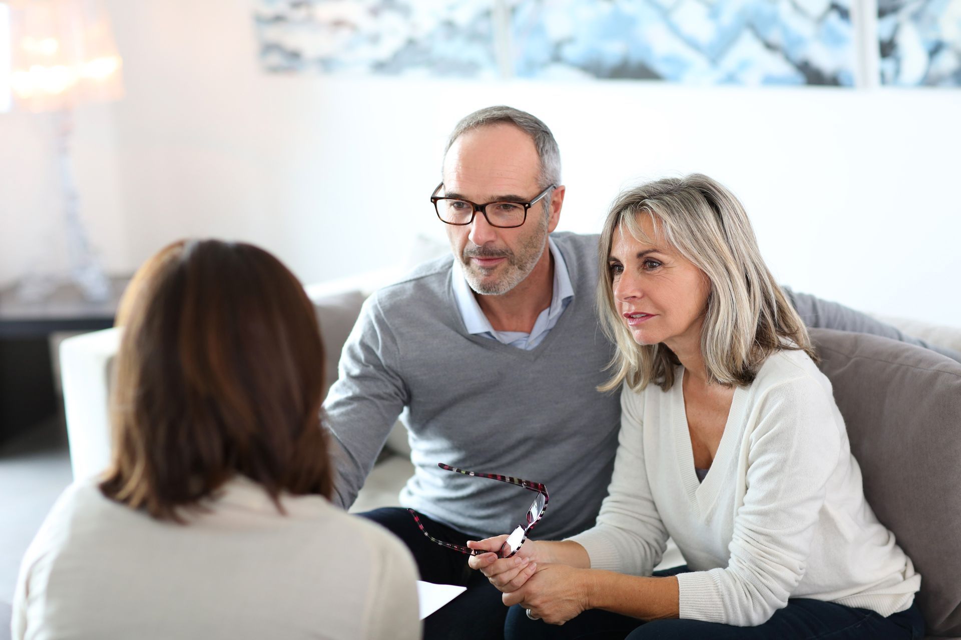 A Man and a Woman Are Sitting on a Couch Talking to a Woman