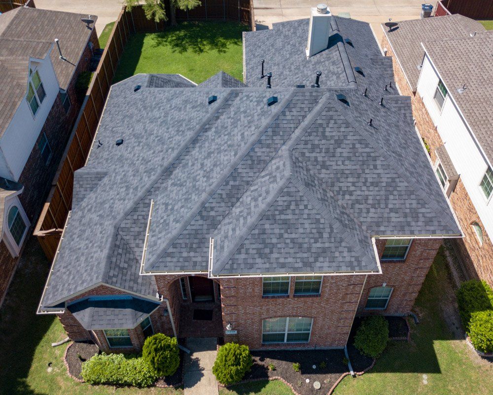 an aerial view of a brick house with a gray roof