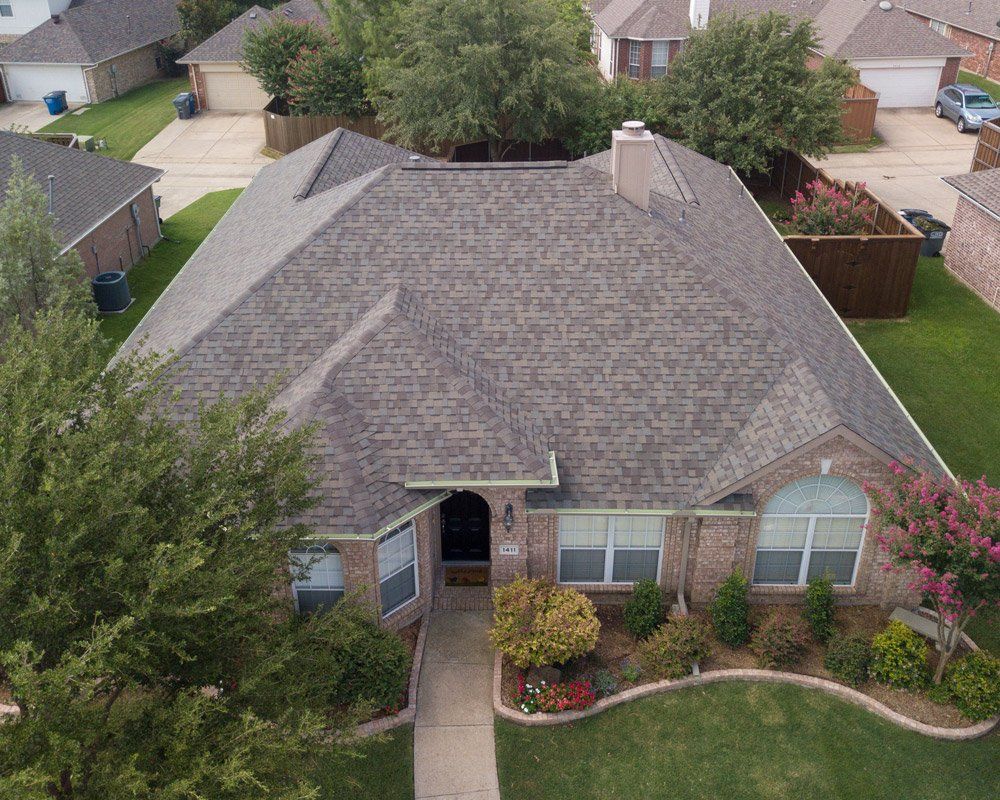 an aerial view of a brick house with a gray roof