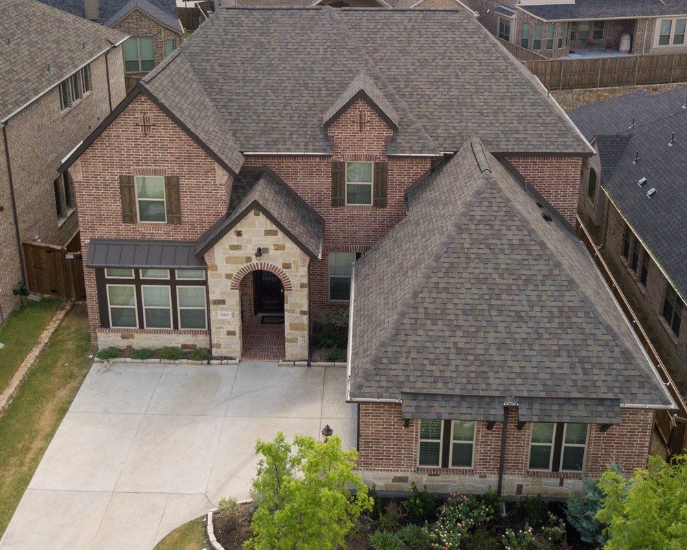 an aerial view of a brick house with a gray roof