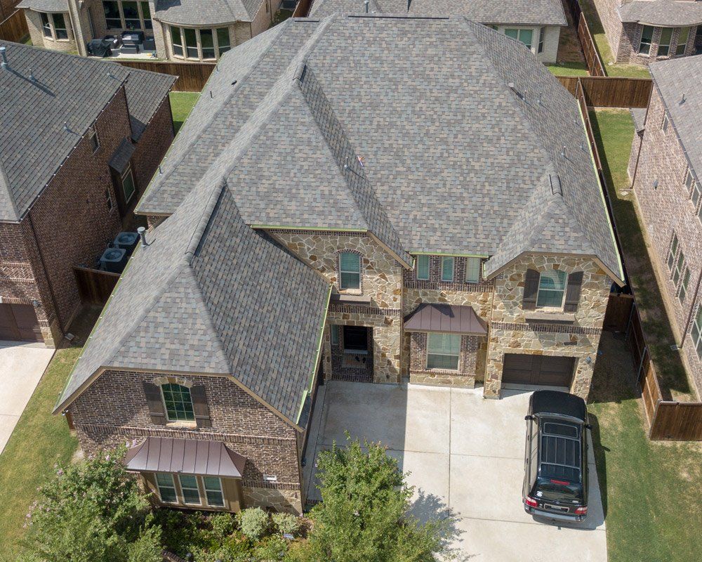 a black suv is parked in front of a large brick house