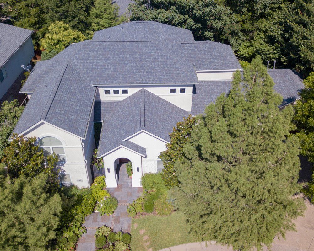 an aerial view of a white house with a gray roof