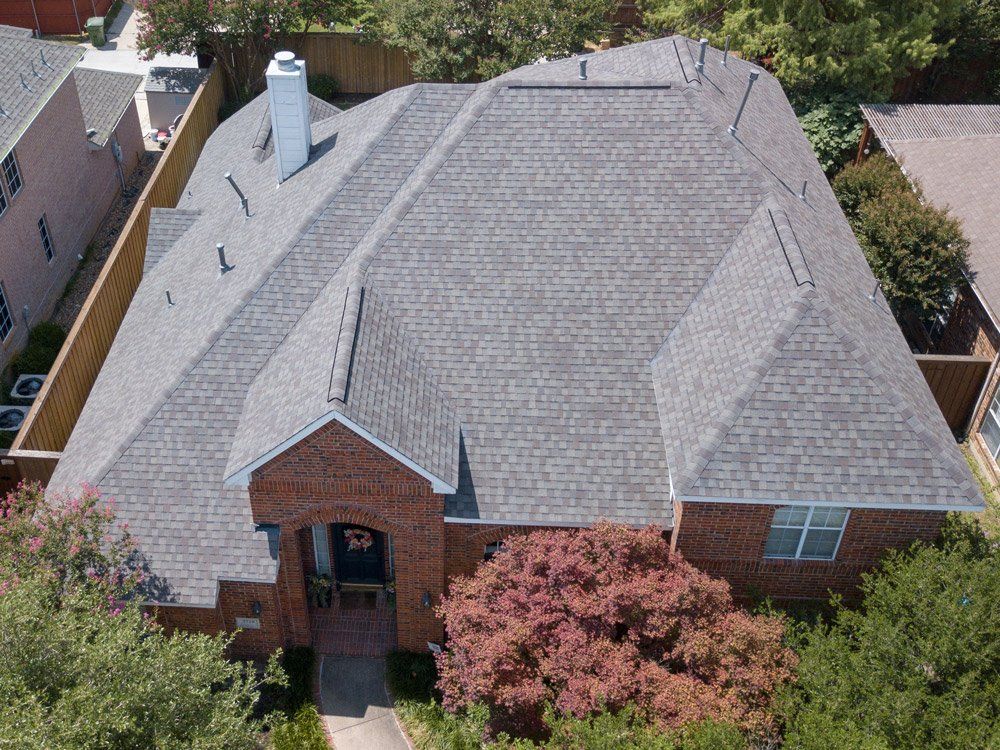 an aerial view of a brick house with a gray roof